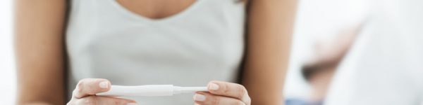 woman looking down at pregnancy test checking results
