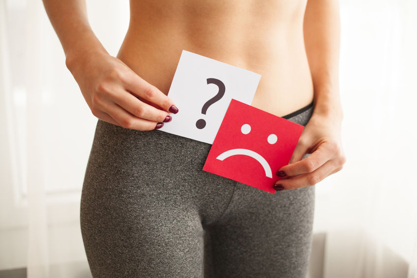 Young woman holds paper with sad smile and question mark above crotch