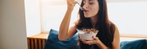 Woman eating yogurt in bed to improve her vaginal health.