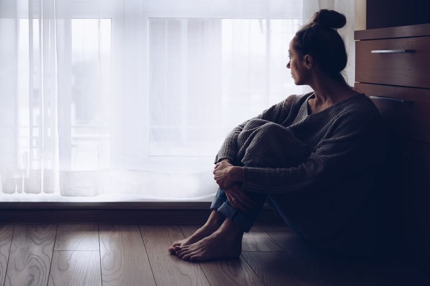 sad woman sitting on floor, grieving an abortion